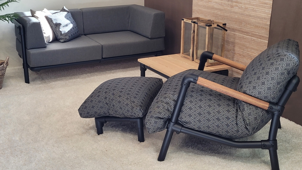 Industriële fauteuil met hocker en patroonstof. De zitstoel heeft houten armleuningen en een zwart buizenframe, perfect als aanvulling op de zithoek.