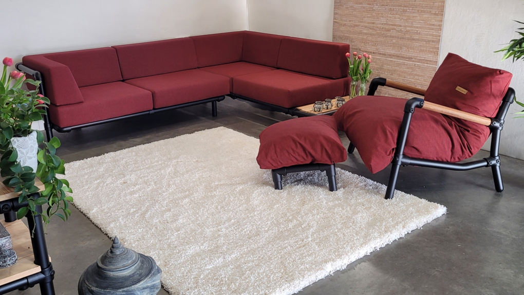 Rode modulaire industriële hoekbank in combinatie met een bijpassende fauteuil en hocker. De hoekopstelling toont de flexibiliteit van onze industriële zitbanken.