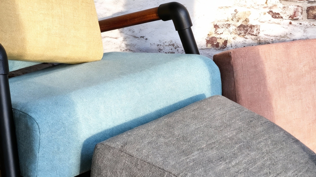 Een overzicht van de duurzame Re-soft stofcollectie in vier kleuren: okergeel, lichtblauw, warm roze en gemêleerd grijs, getoond op industriële meubelstukken met houten details.