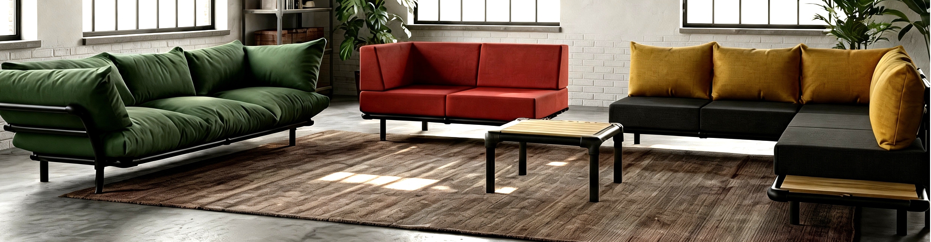 Een ruim industrieel interieur met drie verschillende modellen: een groene Mellow loungebank, een rode Steady zitbank en een zwarte modulaire hoekbank met okergele kussens.