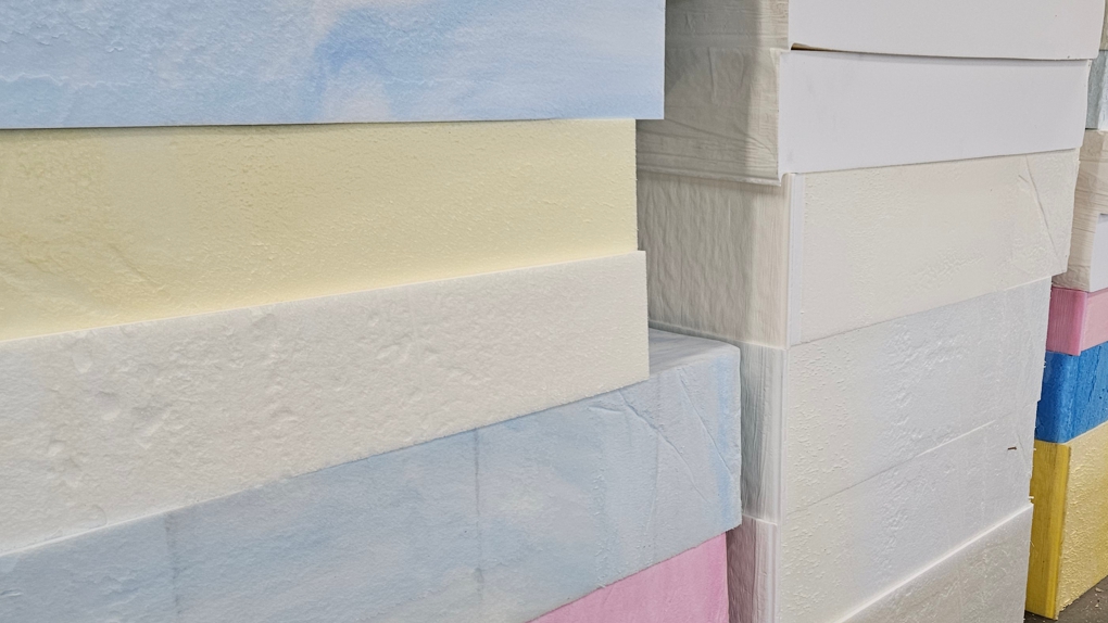 Grote blokken van verschillend gekleurd A-kwaliteit schuimrubber, zoals blauw, wit, geel en roze, opgestapeld voor de productie van bankkussens.