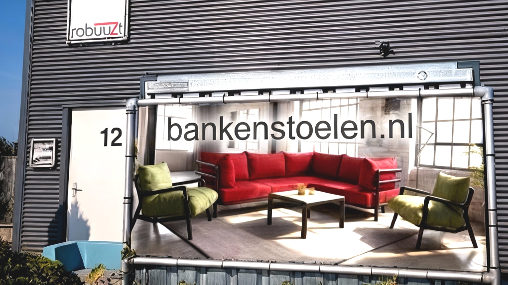 De buitenkant van een modern grijs bedrijfspand met het logo 'Robuuzt' en een grote banner van bankenstoelen.nl.