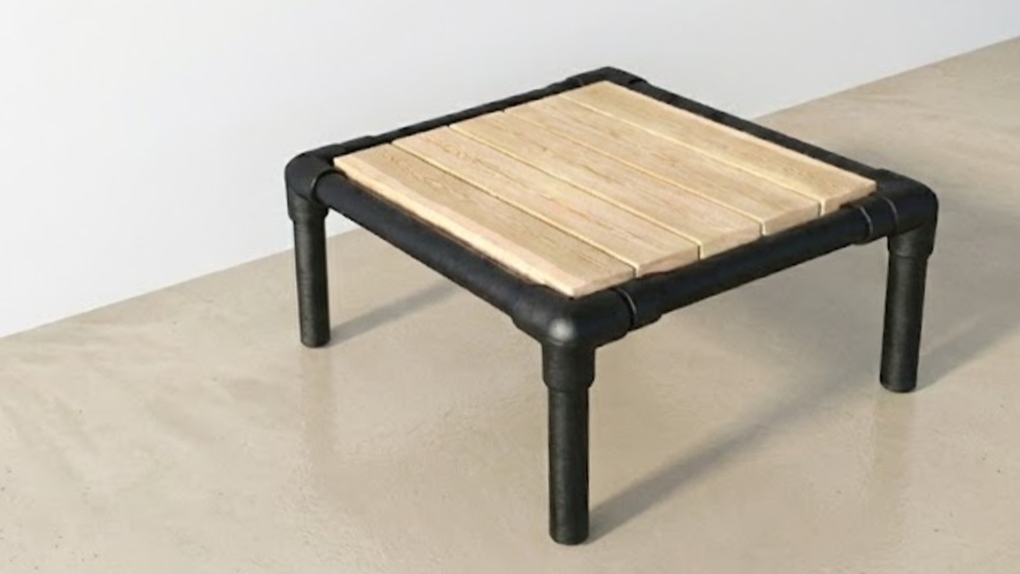 Een vierkante loungetafel met een blad van lichtgekleurd larikshout, gemonteerd op een robuust zwart industrieel onderstel.