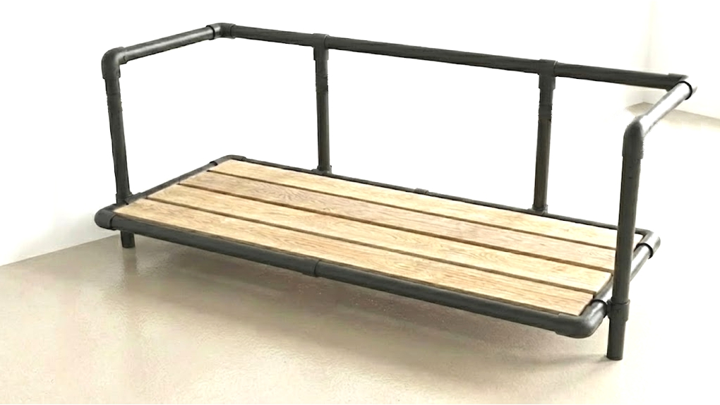 Een zwart industrieel buisframe van een bank waarin een vlonder van lichte Douglashouten planken is gemonteerd als drager voor de kussens.